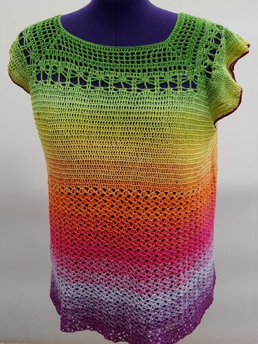 Gehäkeltes Damen-Top in Regenbogenfarben auf einer lila Schneiderpuppe.