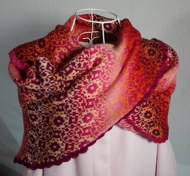 Gestricktes Dreieckstuch mit Jacquard-Muster in Pink-, Orange- und Gelbtönen auf Schneiderpuppe drapiert