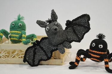 Nahaufnahme: gehäkelte Fledermaus mit Flügeln, gestreifte Spinne und grünes Amigurumi