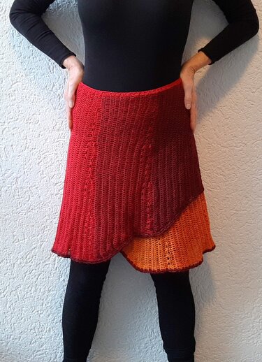 Gehäkelter mehrlagiger Damenrock in Rot‑ und Orangetönen über dunkler Leggings