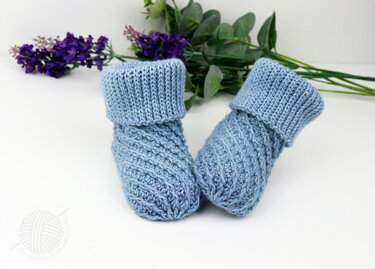 Light blue crochet baby booties with diagonal textured stitch and folded ribbed cuffs