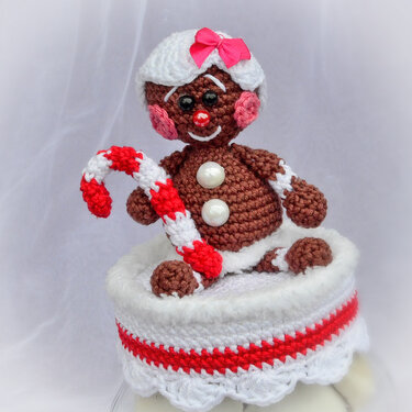 Gehäkelte Lebkuchenfigur mit rosa Schleife und rot-weiß gestreifter Zuckerstange in gehäkeltem Übertopf