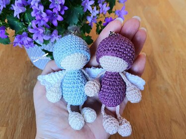 Nahaufnahme zweier gehäkelter Engel-Anhänger mit Metallring in einer Hand