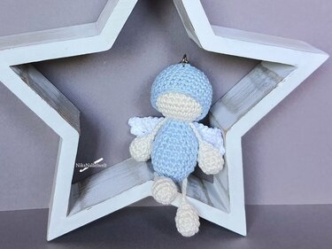 Kleiner gehäkelter Engel in Hellblau und Creme mit Flügeln, platziert in einem weißen Sternrahmen