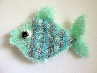 Mintgrüner gehäkelter Fisch aus flauschigem Effektgarn mit silbernen Streifen und aufgesticktem Auge