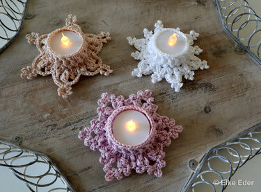 Pastel crochet star tealight holders with warm battery candles arranged on a rustic wooden tray