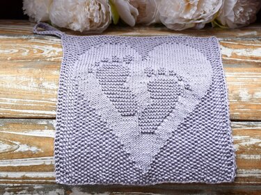 Gestricktes quadratisches Tuch in Flieder mit eingestricktem Babyfuß-Herz und Aufhängeöse