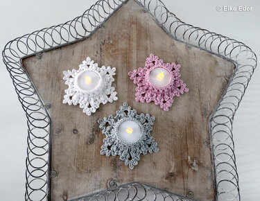 Three small crochet star tealight covers in white, pink and grey around LED tealights