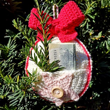 Rundes gehäkeltes rot-weißes Weihnachtstäschchen mit Schleife, Außentasche und Holzknopf