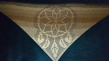Beiges, dreieckiges Filet-Häkeltuch mit floralem Mittelmuster auf dunklem Hintergrund