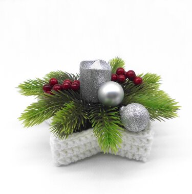 White crocheted star basket decorated with faux pine sprigs, red berries, a silver candle and silver ornament balls