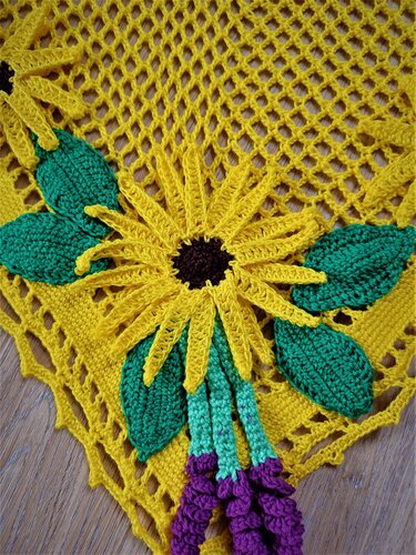 Gelbes gehäkeltes Deckchen mit applizierter Sonnenblume, grünen Blättern und violetten Verzierungen auf Netzgrund