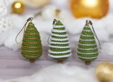 Drei grüne gehäkelte Mini-Weihnachtsbäume mit goldenen, weißen und silbernen Zierstreifen und Aufhängeschlaufen