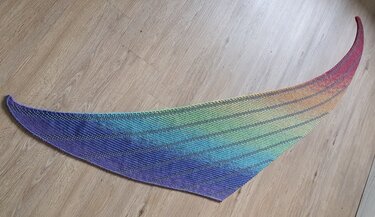 Asymmetrisches gestricktes Dreieckstuch mit Regenbogen-Farbverlauf auf Holzfußboden