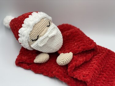 Crocheted Santa doll wrapped in a red plush baby snuggle blanket