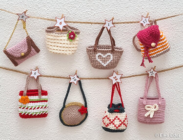 Row of small crocheted purses and bags hung on twine with numbered star clips for an Advent calendar
