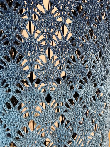 Close-up of ombre blue crochet lace shawl with open, airy stitches.