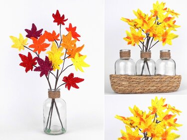 Crocheted maple leaves in red, burgundy, orange, and yellow on stems arranged in clear glass bottles and a woven basket.