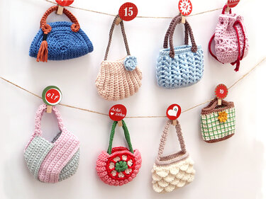 Row of small crocheted purses clipped to string with numbered Christmas tags