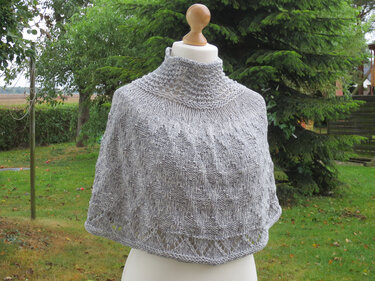 Hellgrauer gestrickter Poncho mit hohem Kragen auf Schneiderpuppe