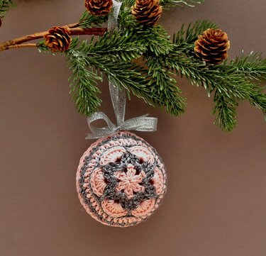 Gehäkelte Weihnachtskugel im African
Flower
Muster, rosa und grau, hängend an Tannenzweig