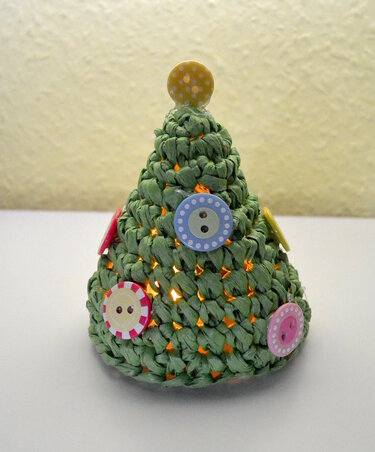 Grüner gehäkelter Mini-Weihnachtsbaum mit bunten Knöpfen und warmem Innenlicht