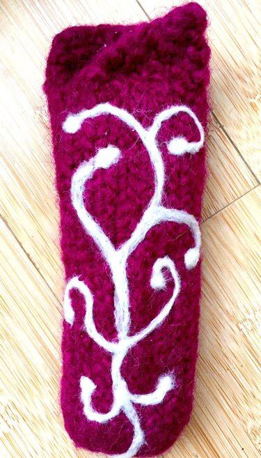 Magenta Filz-Etui mit weißem Rankenmuster auf hellem Holz