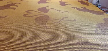 Mustard-yellow knitted blanket with brown horse silhouettes and horizontal rib stitch