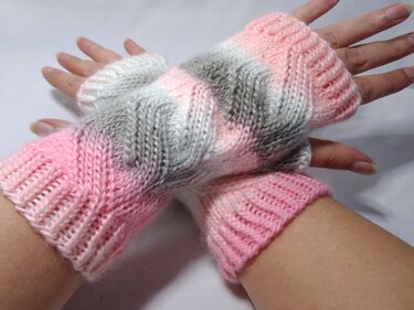 Fingerlose Strickhandschuhe in Rosa, Grau und Weiß an Händen