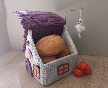 Gehäkeltes Haus-Brotkörbchen in Grau und Lila mit Brötchen, kleinen gehäkelten Kürbissen, Spinnen und einem hängenden Gespenst