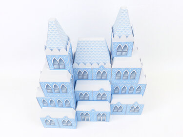 Hellblau-weißer Adventskalender in Form eines mehrteiligen Märchenschlosses aus Papier, mit nummerierten Türchen und Fensterdetails.
