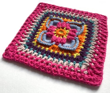 Quadratisches, mehrfarbiges Häkelmuster mit erhabener Blumenmitte in Pink, Orange und Pastelltönen