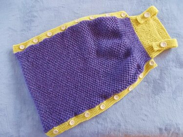 Violetter gestrickter Babyschlafsack mit gelber Blende und Knopfleiste