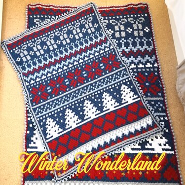 Zwei übereinandergelegte gehäkelte Decken mit blau‑rot‑weißem Wintermuster, Schneeflocken und Tannenbäumen