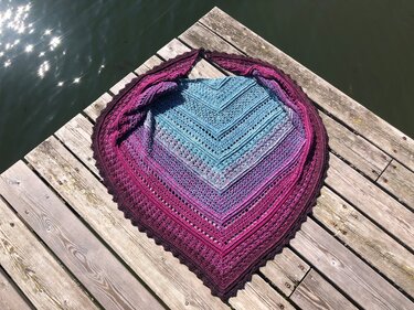 Gehäkeltes Dreieckstuch mit Farbverlauf von Blau zu Violett auf einem Holzsteg