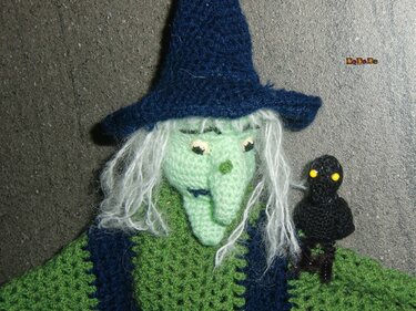 Gehäkelte Hexe mit grünem Gesicht, blauem Hut und kleinem schwarzem Raben