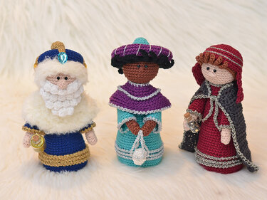 Drei gehäkelte Weihnachtsfiguren, die die Heiligen Drei Könige in traditionellen Gewändern mit Gaben darstellen.