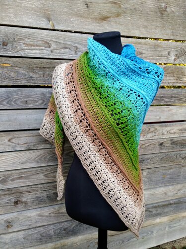 Gehäkeltes dreieckiges Tuch in Blau‑Grün‑Braun mit Spitzenrand auf schwarzer Schaufensterpuppe
