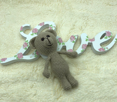 mini Amigurumi Teddybär mit einfachen Proportionen auf flauschiger Oberfläche