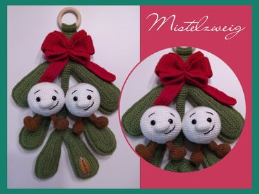 Gehäkelter Mistelzweig Amigurumi mit zwei weißen Beeren, grünen Blättern, roter Schleife und Holzring