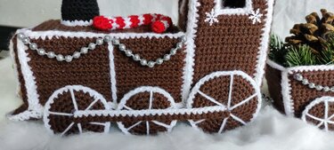Gehäkelter brauner Lebkuchenzug mit weißen Zierkanten, Perlenkette und Zuckerstange