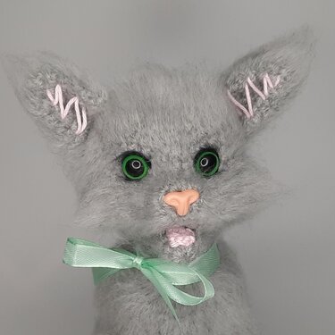 Grau gehäkelte Amigurumi
Katze mit grünen Augen, rosa Nase und mintgrünem Band