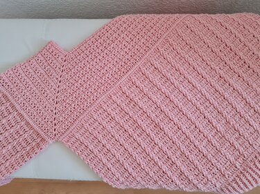 Rosa gehäkelter Poncho liegend mit V‑Ausschnitt und reliefartigem Muster
