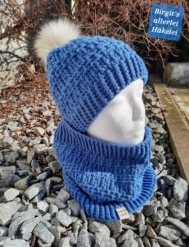 Blaues gehäkeltes Damen-Set mit Bommelmütze und Loop auf weißem Mannequinkopf