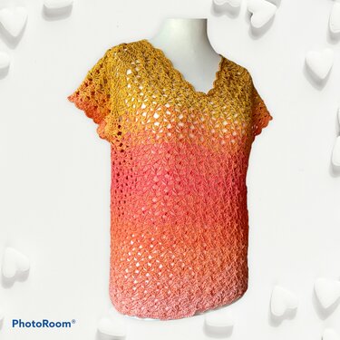 Gehäkeltes Damen-Shirt in Ombre-Farben (Gelb–Orange–Rosa) mit V-Ausschnitt und kurzen Ärmeln auf Schaufensterpuppe.