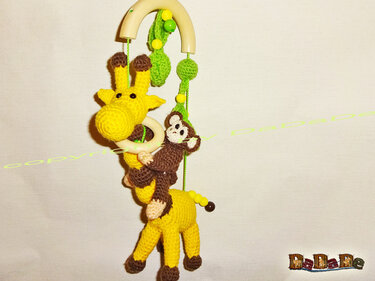 Gehäkeltes Mobile mit gelber Giraffe, braunem Affen, grünen Blättern und Holzring