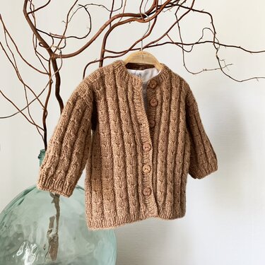 braune gestrickte Kinderjacke mit Strukturmuster und Holzknöpfen an einem Holzbügel
