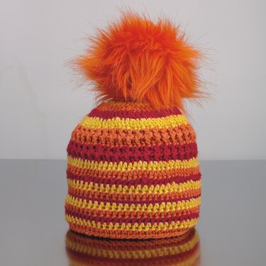 Gehäkelte Kinder-Mütze mit gelb-orange-roten Streifen und orangefarbenem Bommel