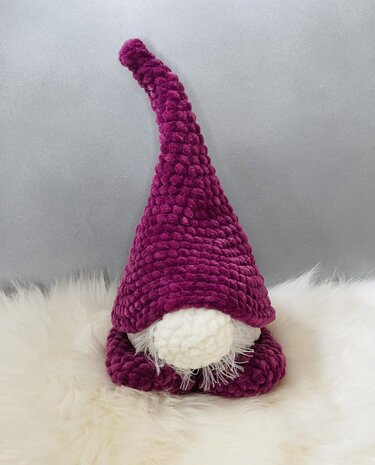 Gehäkelter Wichtel in Beerenton mit hoher spitzer Mütze, weißer runder Nase und flauschigem Bart