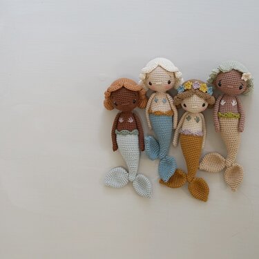 Vier Amigurumi-Meerjungfrauen nebeneinander, Maschenstruktur und Flossen sichtbar